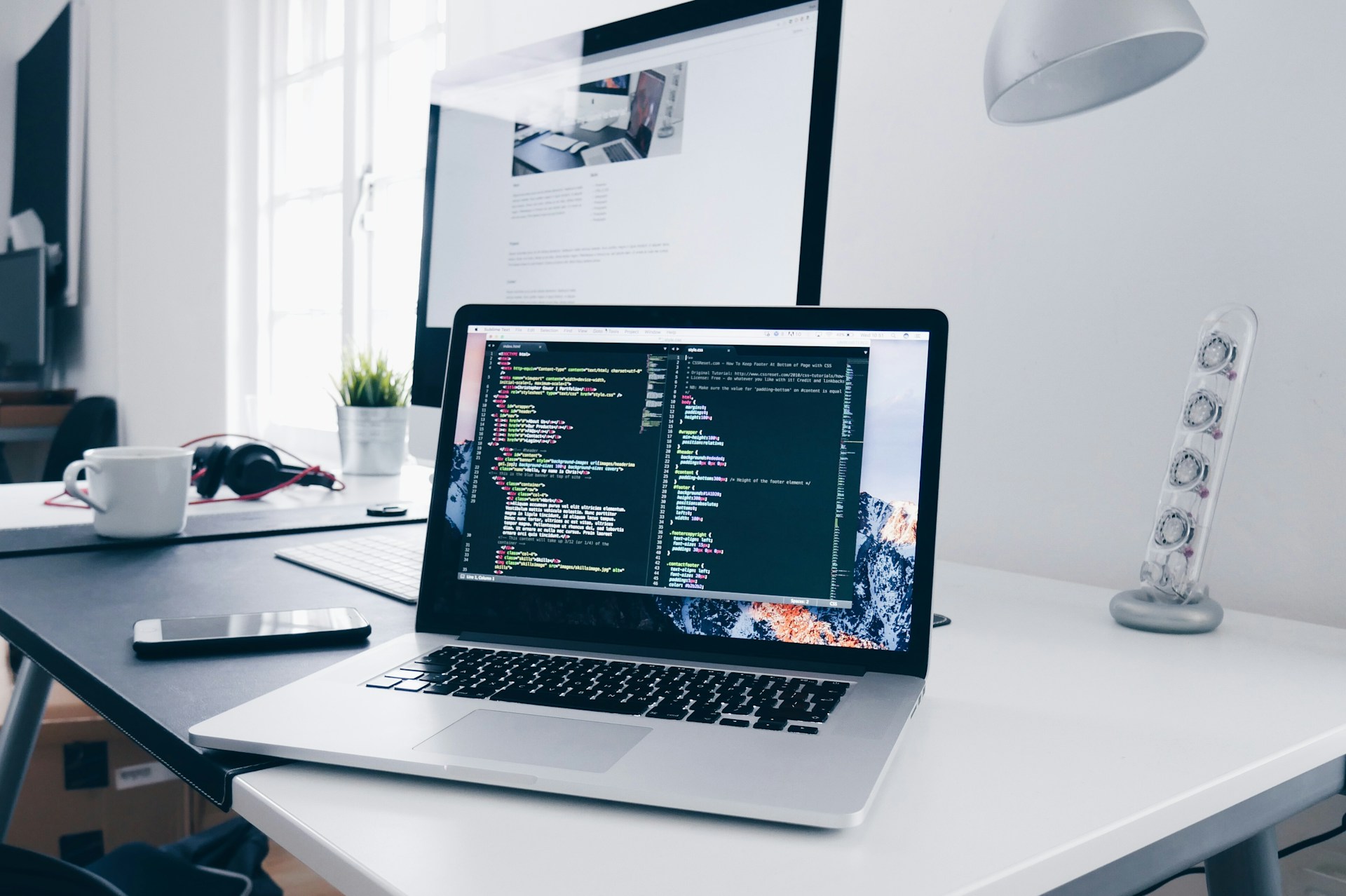 en open laptop som står på en pult og har html coder på skjermen
